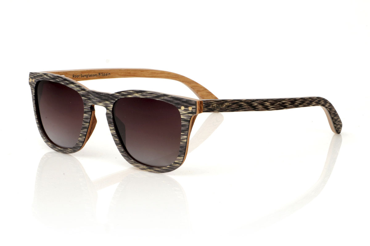 Wood eyewear of Jichimu RISKY. RISKY wooden sunglasses combine a classic shape that flatters all face types with a more contained size, creating a versatile and always on-trend accessory. They are meticulously manufactured using a three-strip laminate technique: black Chicken Wing wood on the outside, maple in the center that provides luminosity, and oak on the inside, offering exceptional resistance. The temples replicate this tricolor pattern, guaranteeing coherence and style throughout the entire set. What really makes the RISKY stand out is the unique texture of its front, accented with eye-catching oak rivets. Measuring 140x47mm and a caliber of 49, these glasses are the perfect balance between comfort and style statement. for Wholesale & Retail | Root Sunglasses® 